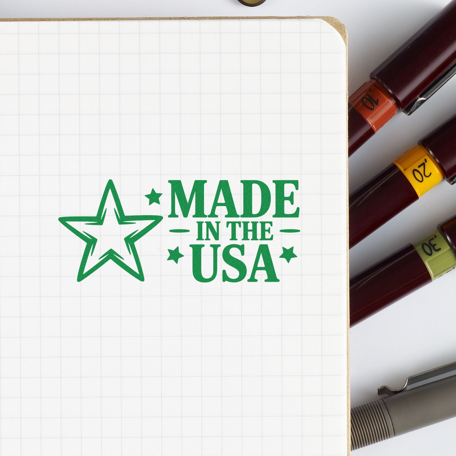 Green Made in the USA stamp beside burgundy, orange, yellow, and olive seal markers on a white grid notebook.