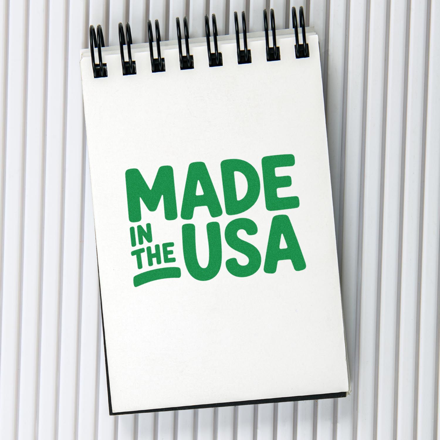 White spiral-bound stamp seal featuring green Made in the USA text on a white ribbed background.