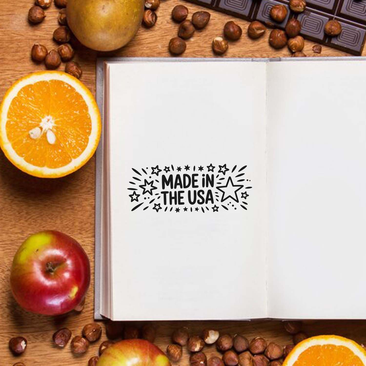 Black Made in the USA stamp seal on an open white book, with oranges, apples, and coffee beans on wood.