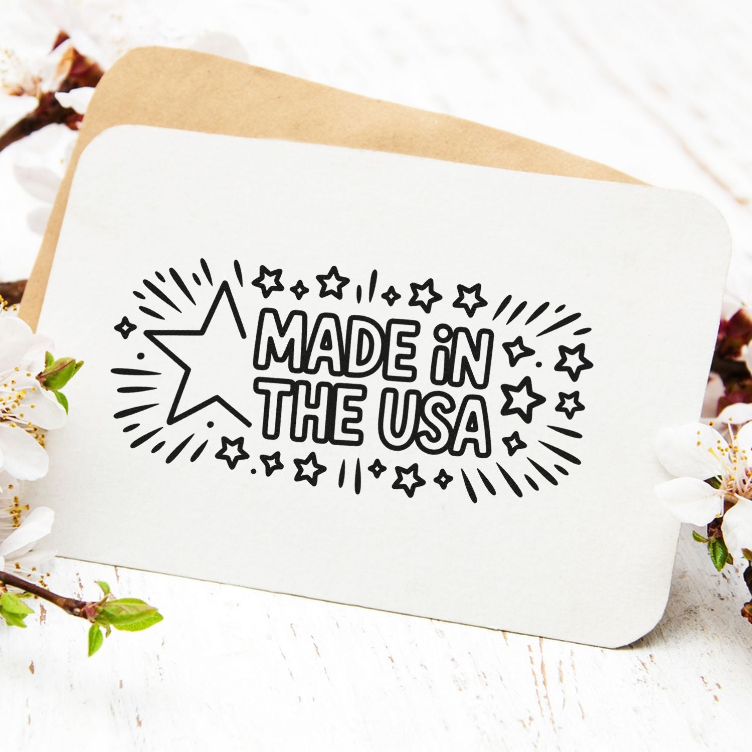 White stamp seal card with black Made in the USA text, starburst accents, and tan backing on a floral tabletop.