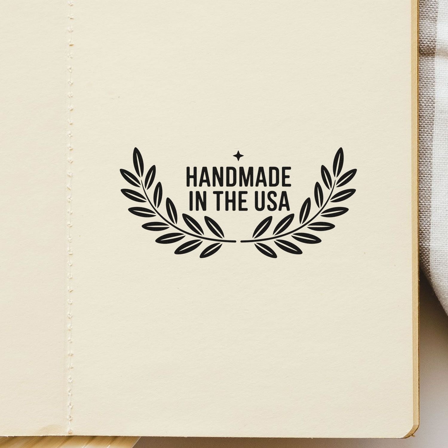 Black handmade in the USA stamp seal with laurel leaves on cream paper notebook page.