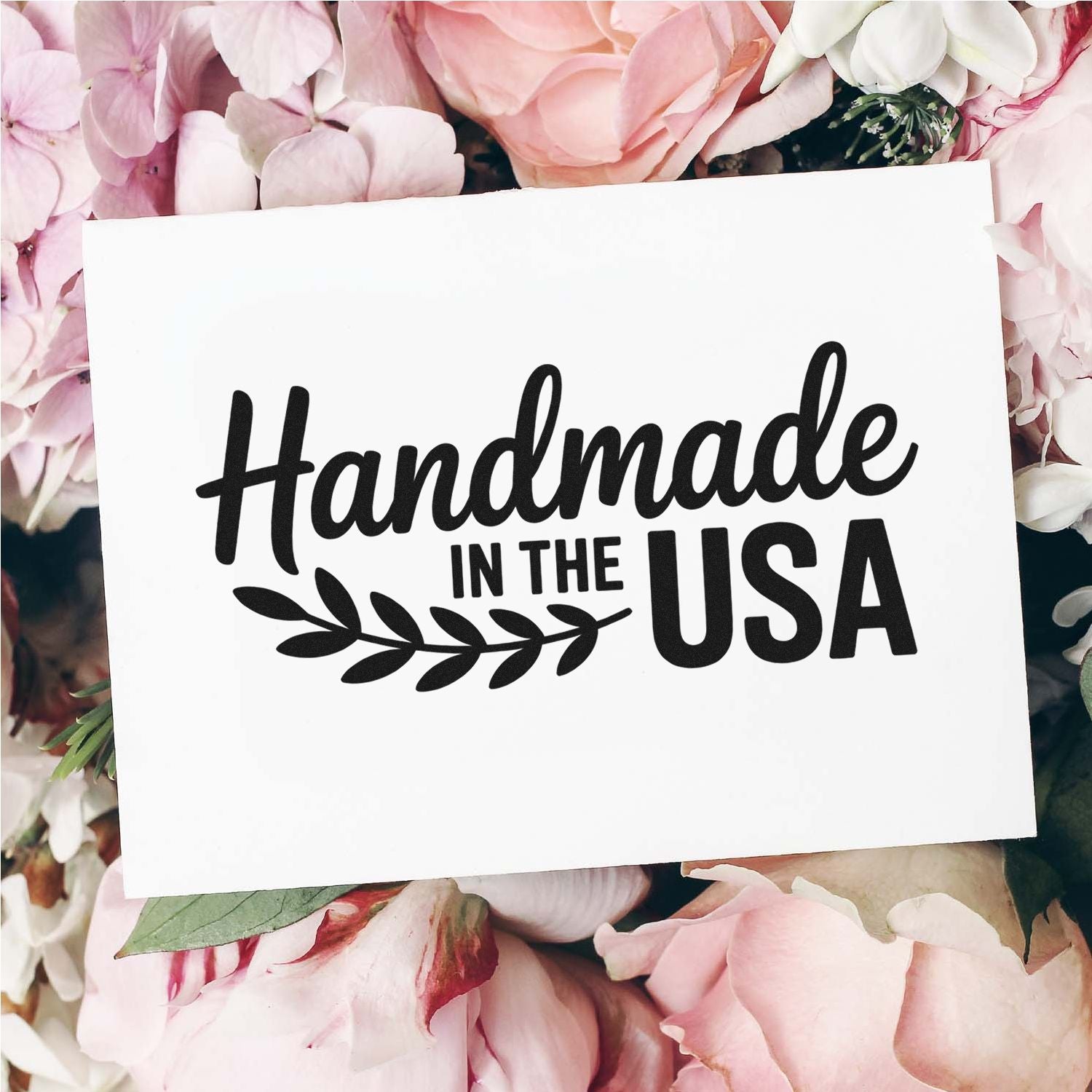 Black Handmade in the USA stamp and seal on white card, framed by soft pink and white flowers.