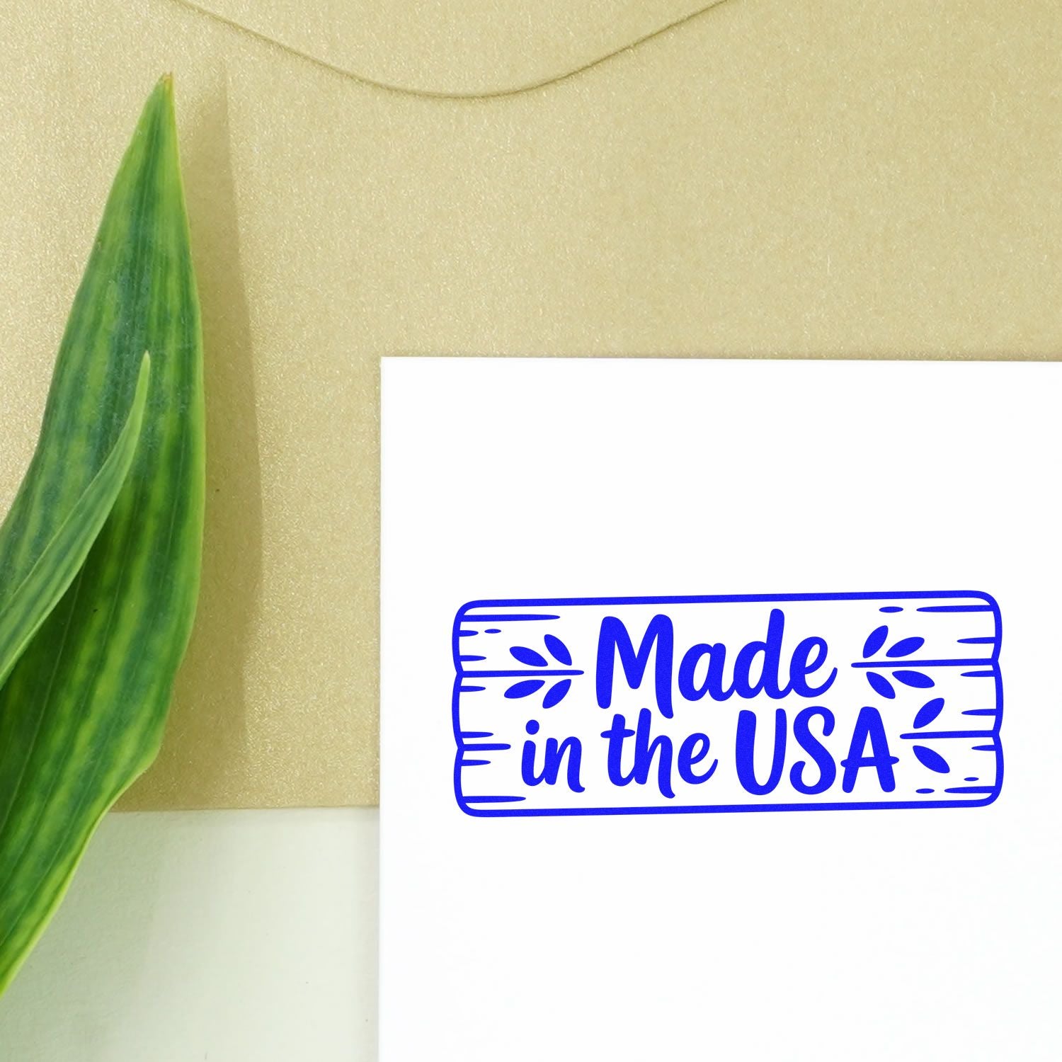 Blue Made in the USA stamp and seal on white card beside a green leaf on a beige background.