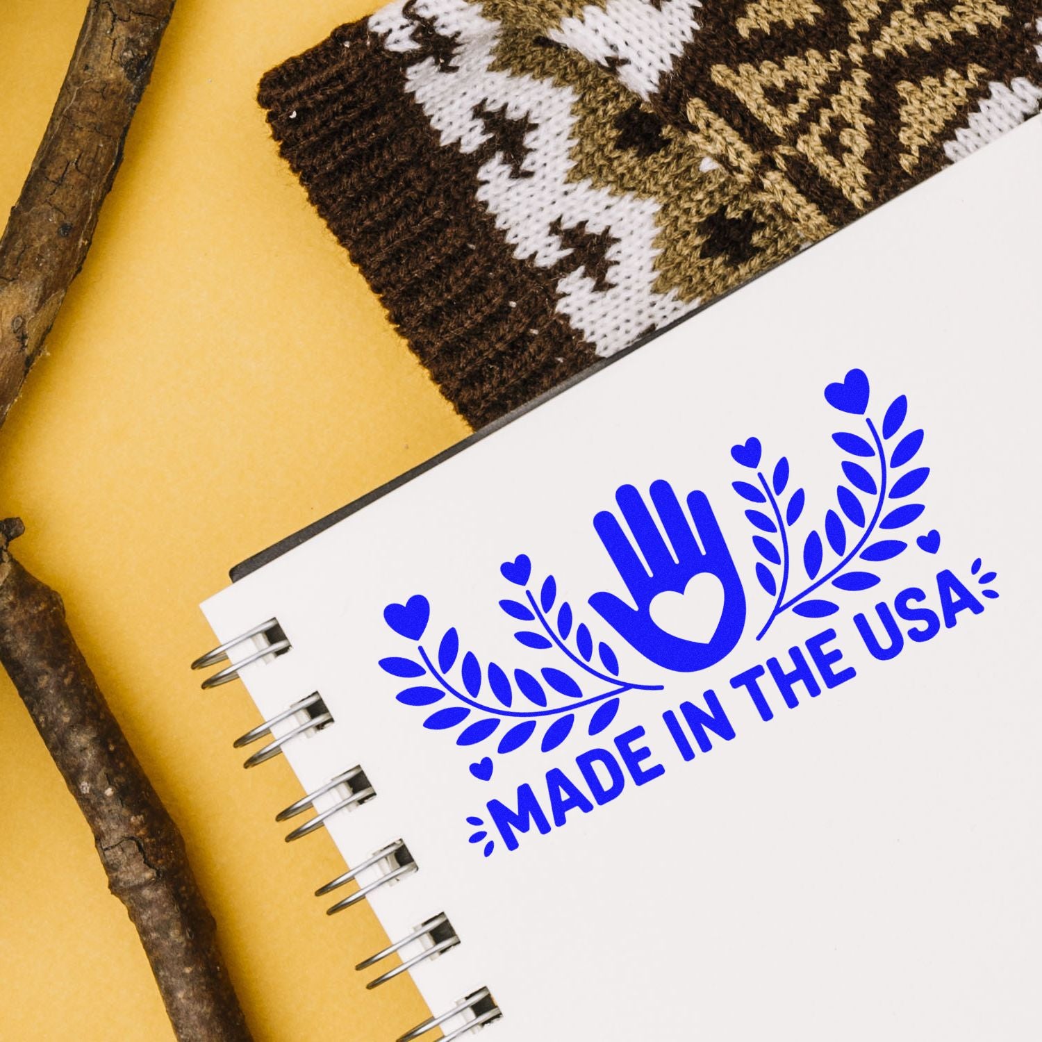 Blue Made in the USA stamp seal on a white spiral notebook, with heart and leaf design on a warm yellow background.