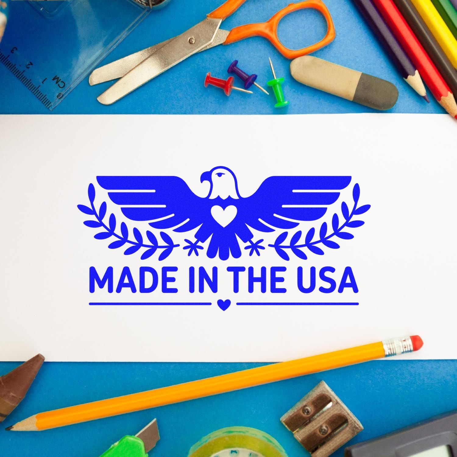 Blue Made in the USA eagle stamp seal on white paper, surrounded by school supplies and stationery.