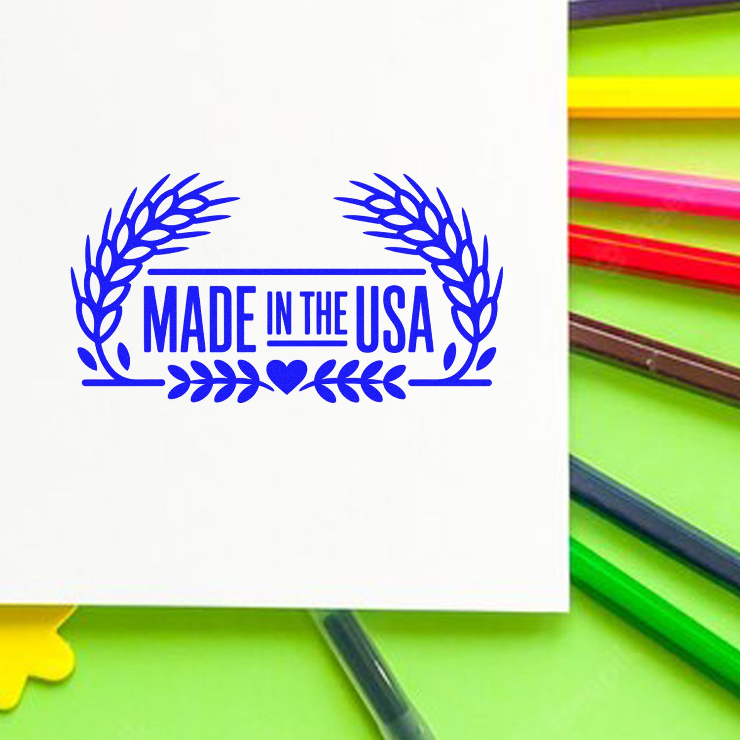 Blue Made in the USA stamp and seal design with laurel wreath and heart on white, beside colorful ink pads.
