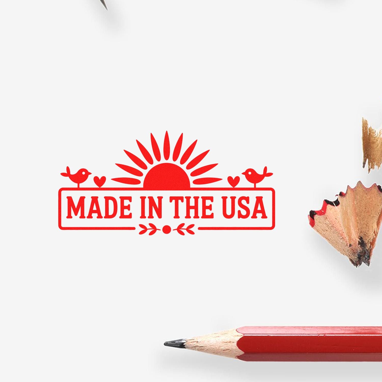 Red Made in the USA stamp seal with sunburst, birds, and hearts beside a red pencil on white background.