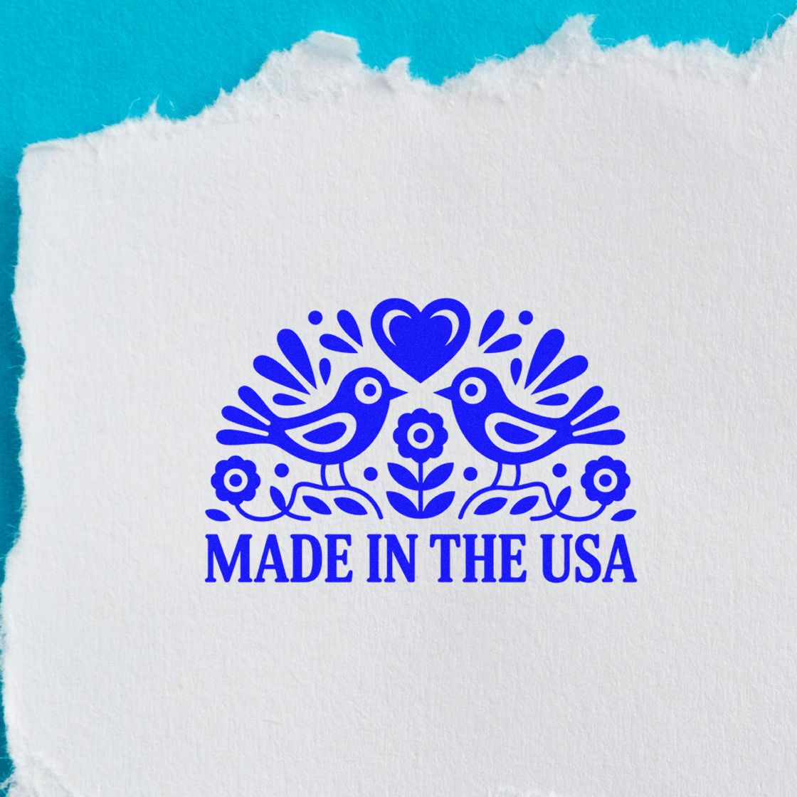 Blue Made in the USA stamp seal with two birds, heart, and flowers on white textured paper.