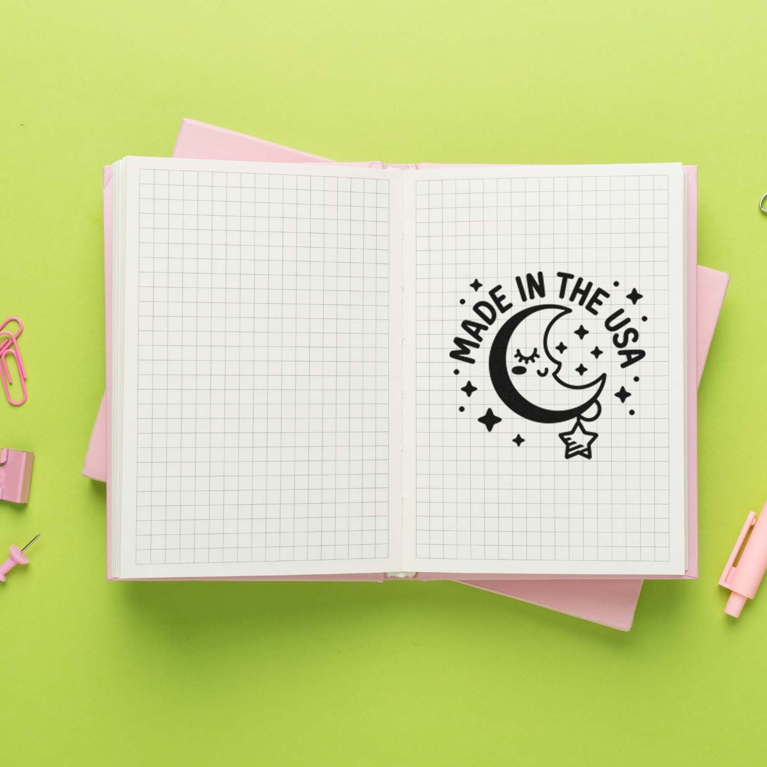 Custom stamp and seal sample: black Made in the USA moon-and-stars stamp on open grid notebook, with lime green and pink accents.