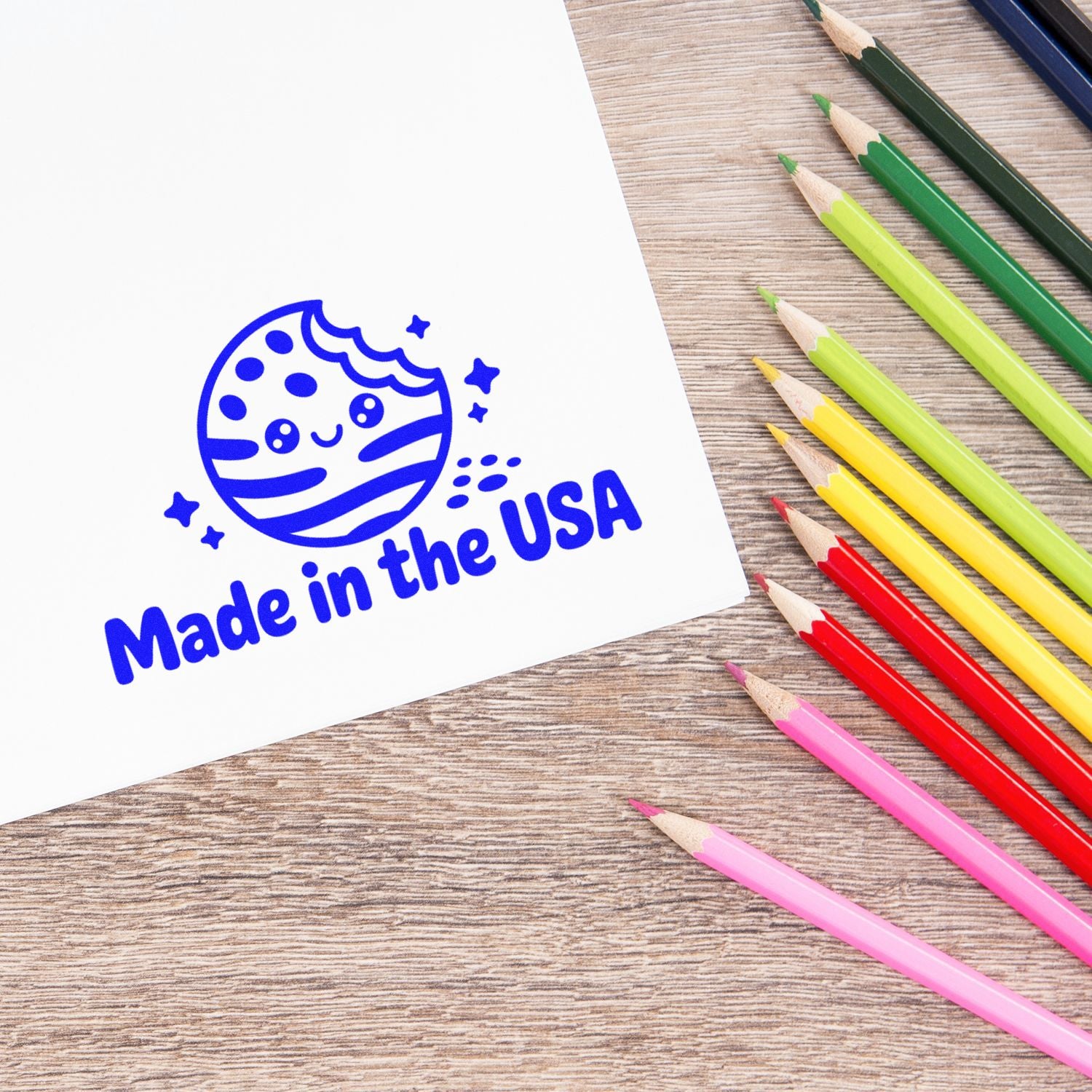Blue Made in the USA stamp seal on white paper, with colorful pencils on a wood desk.