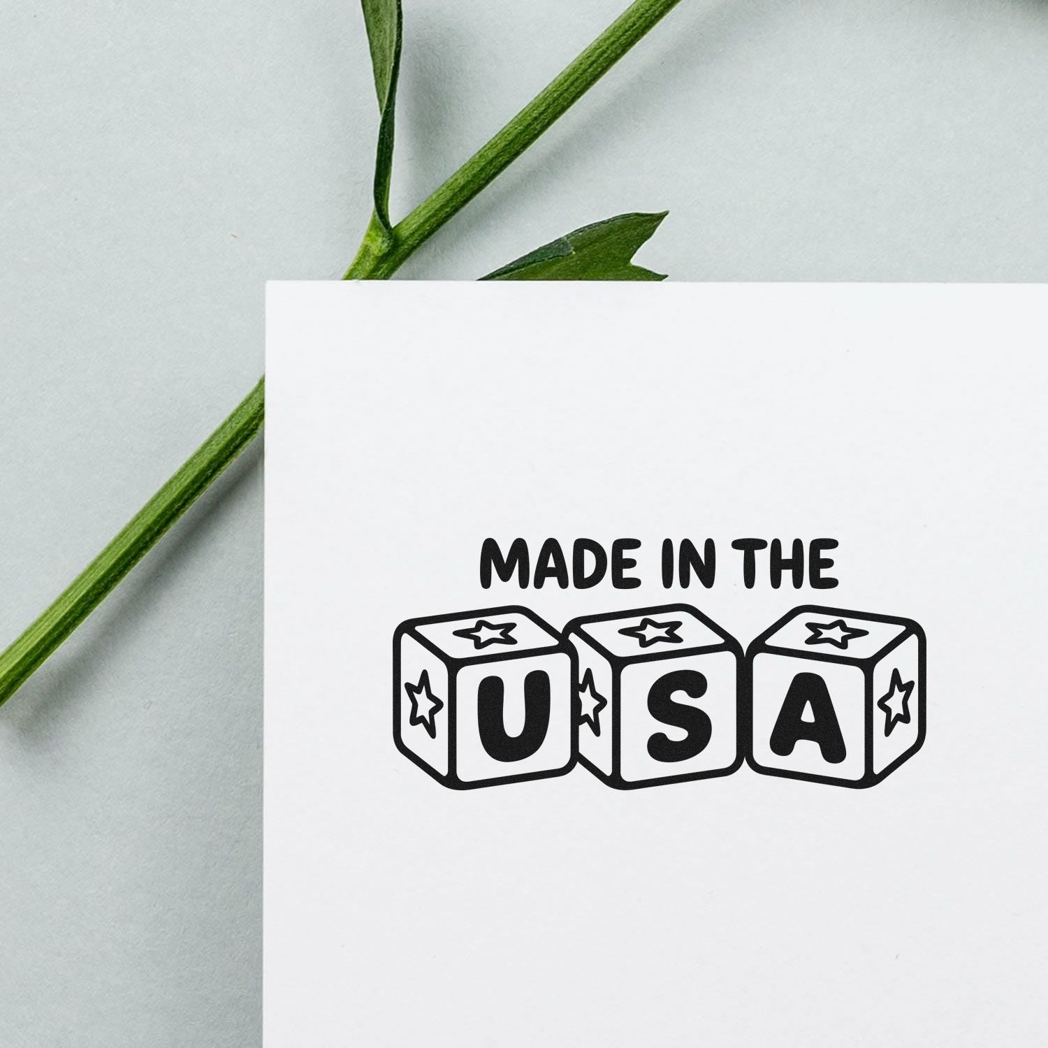 Black Made in the USA stamp and seal design on white card with green stem and pale background