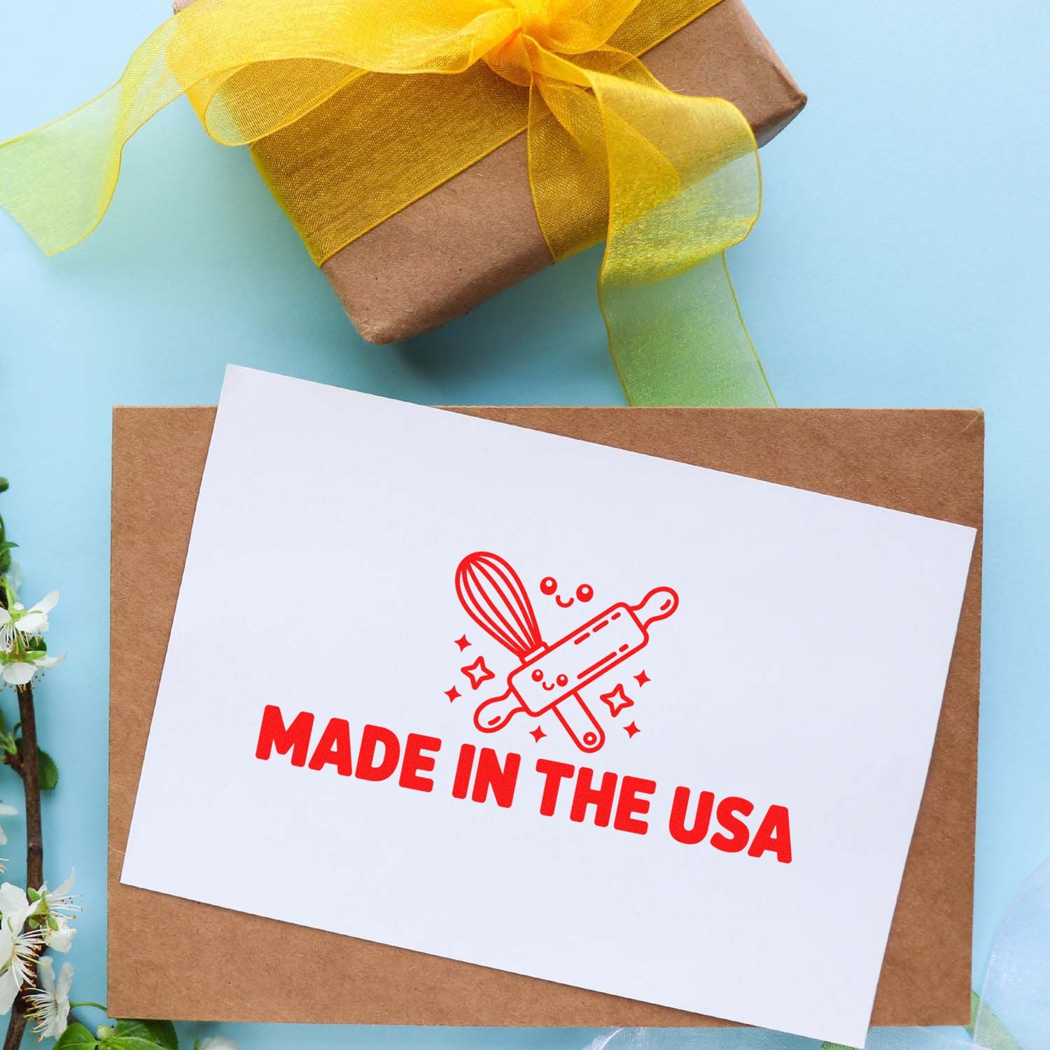 Custom stamp and seal card with red Made in the USA imprint on kraft envelope, yellow ribbon gift box on light blue background.