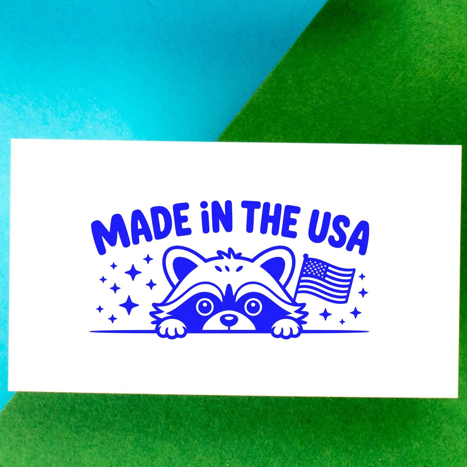 Blue Made in the USA stamp and seal design with a raccoon, stars, and U.S. flag on a white card.