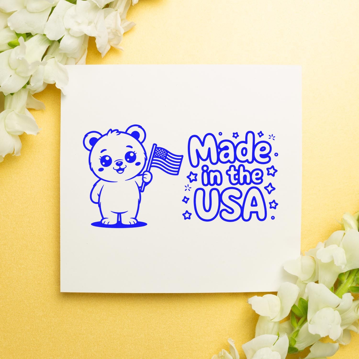 Blue Made in the USA stamp seal with bear holding an American flag on a white square, set on a yellow background with white flowers.