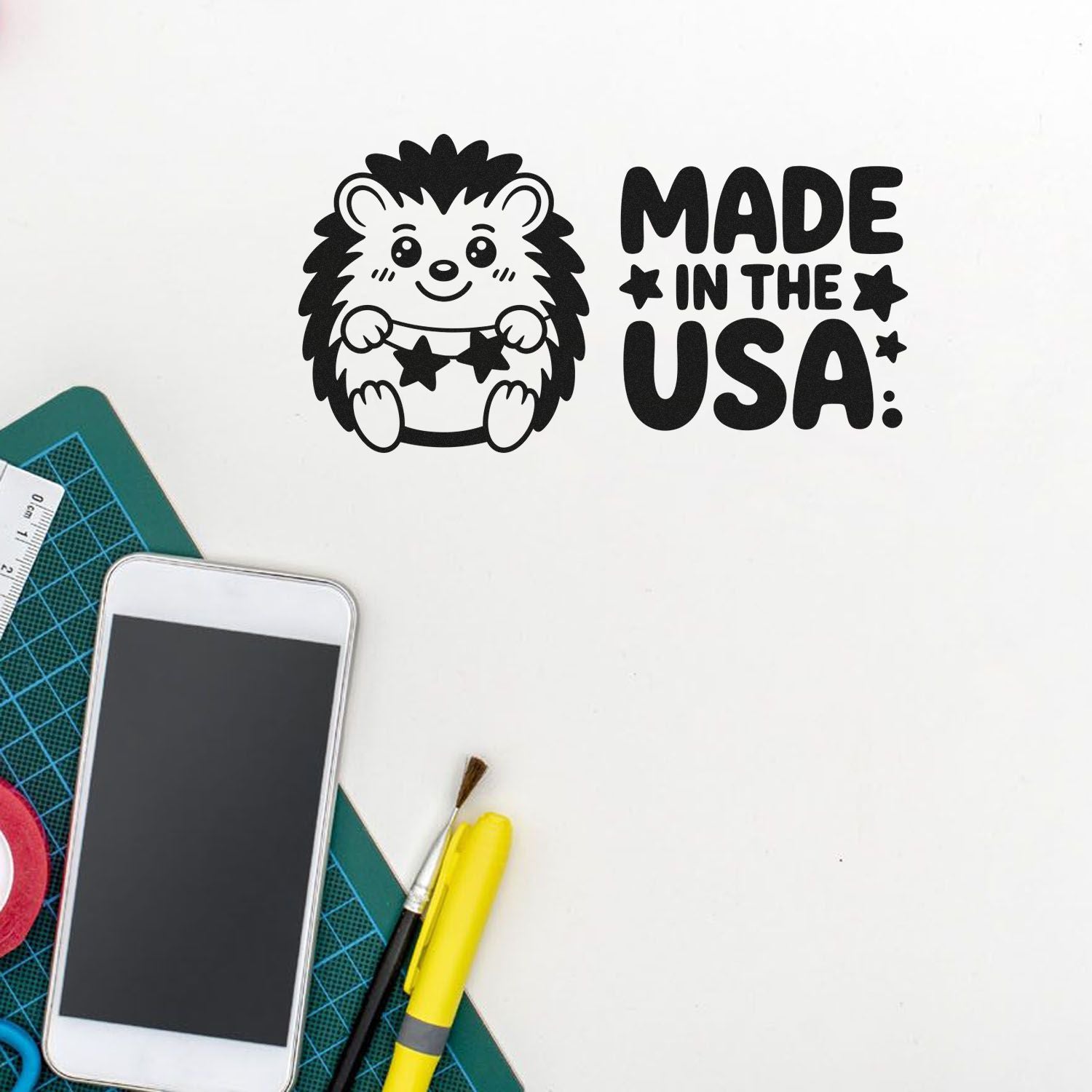 Black Made in the USA hedgehog stamp and seal design with stars, on a white craft table with tools.