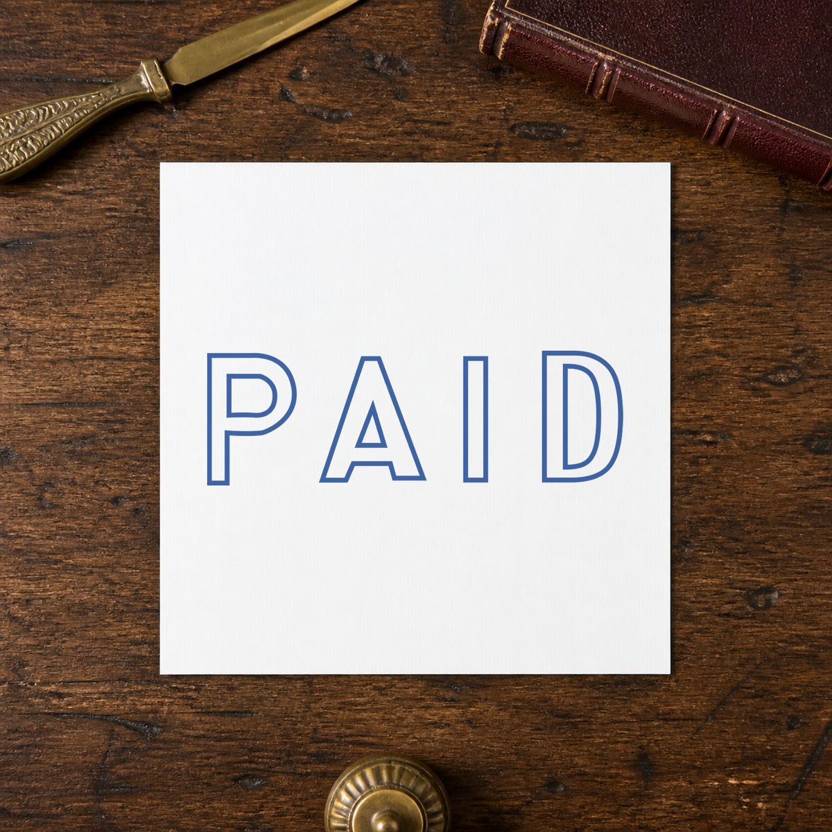 Pre-inked "Paid" stamp marking paperwork in an office setting