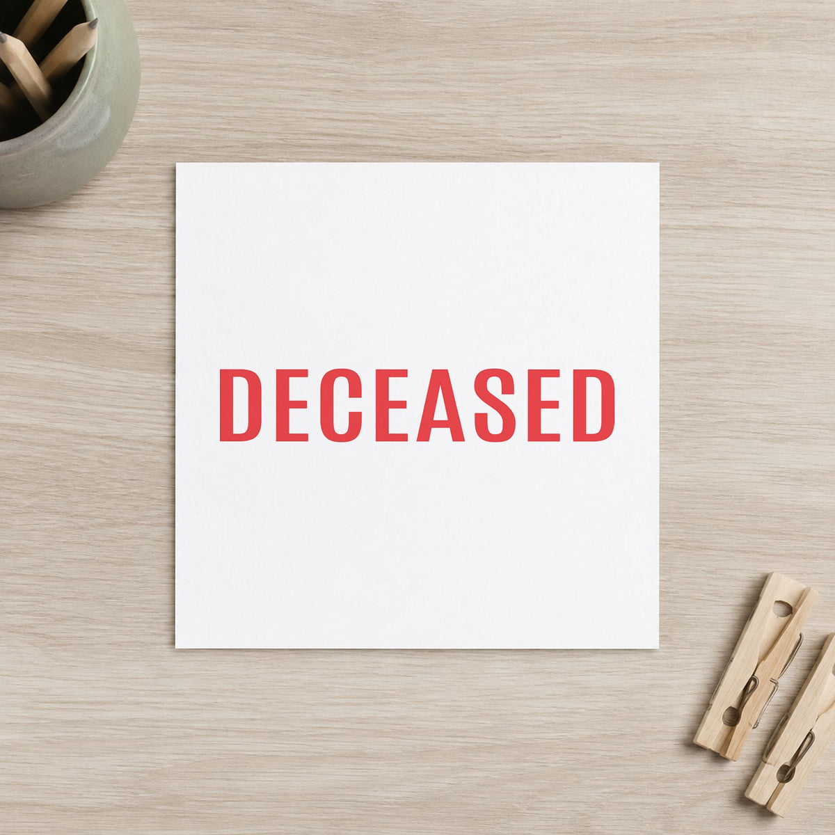 Pre-inked "Deceased" stamp marking paperwork in an office setting