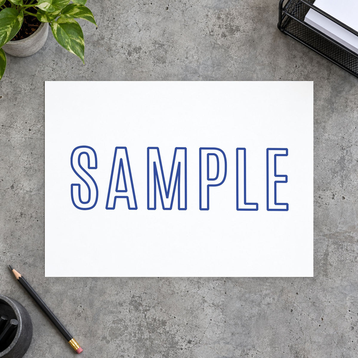 "Sample" Xstamper stamp in use on paper, 1/2 x 1-5/8 in rectangle imprint
