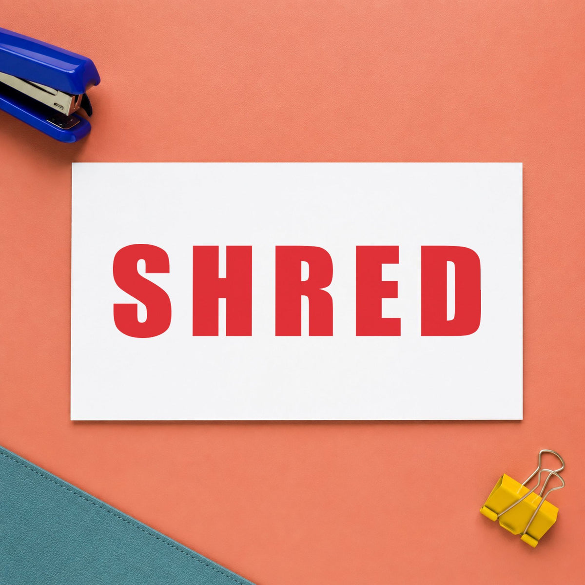 Pre-inked "Shred" stamp marking paperwork in an office setting
