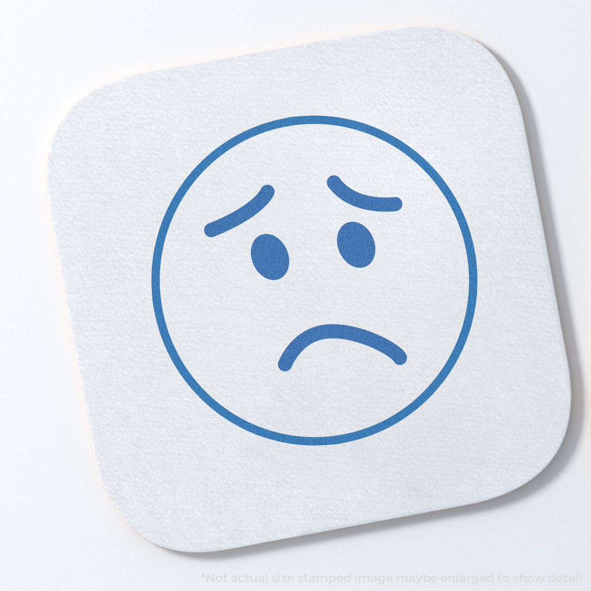 "Frown face" stamp and its crisp 5/8 in diameter impression on paper