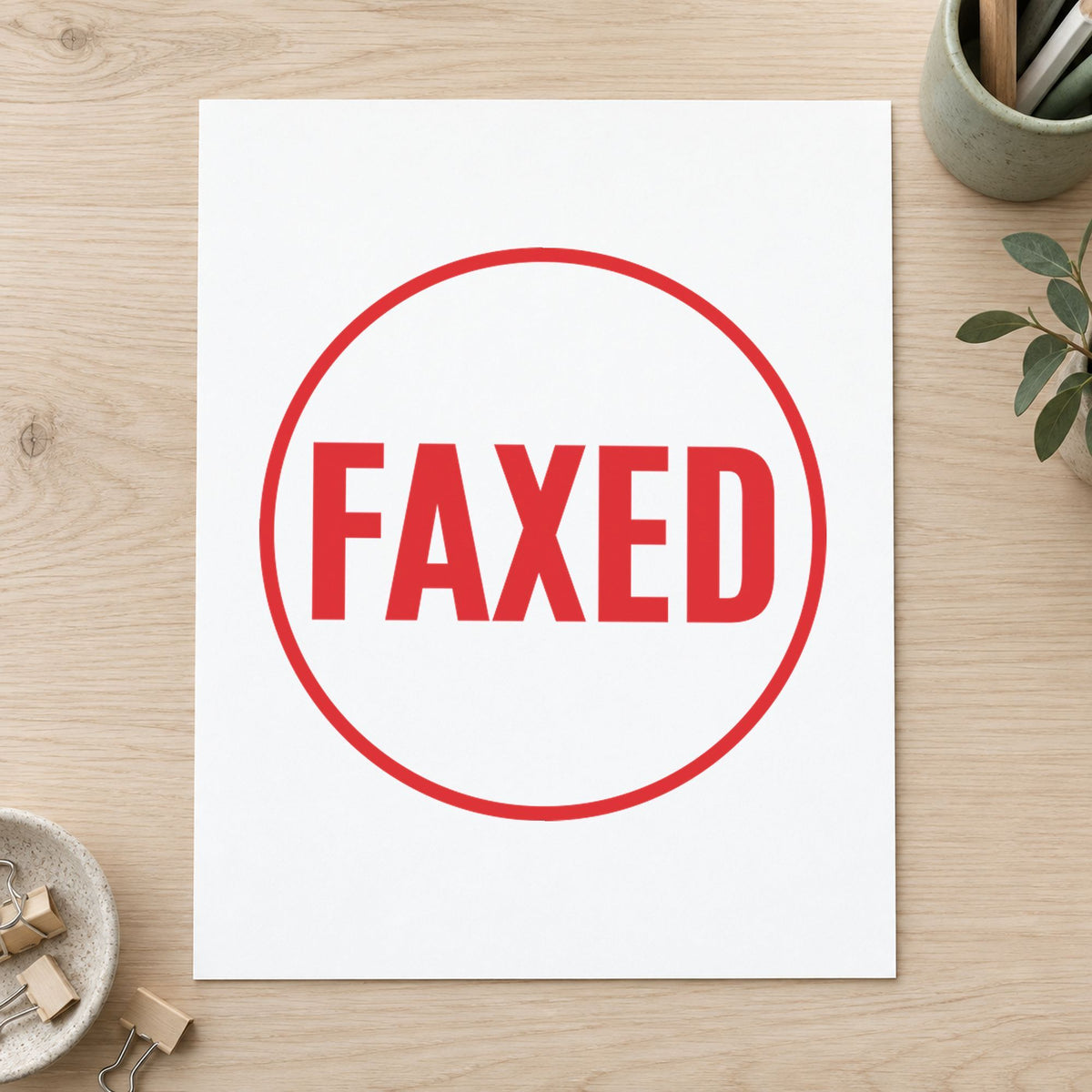 Pre-inked "Faxed" stamp marking paperwork in an office setting
