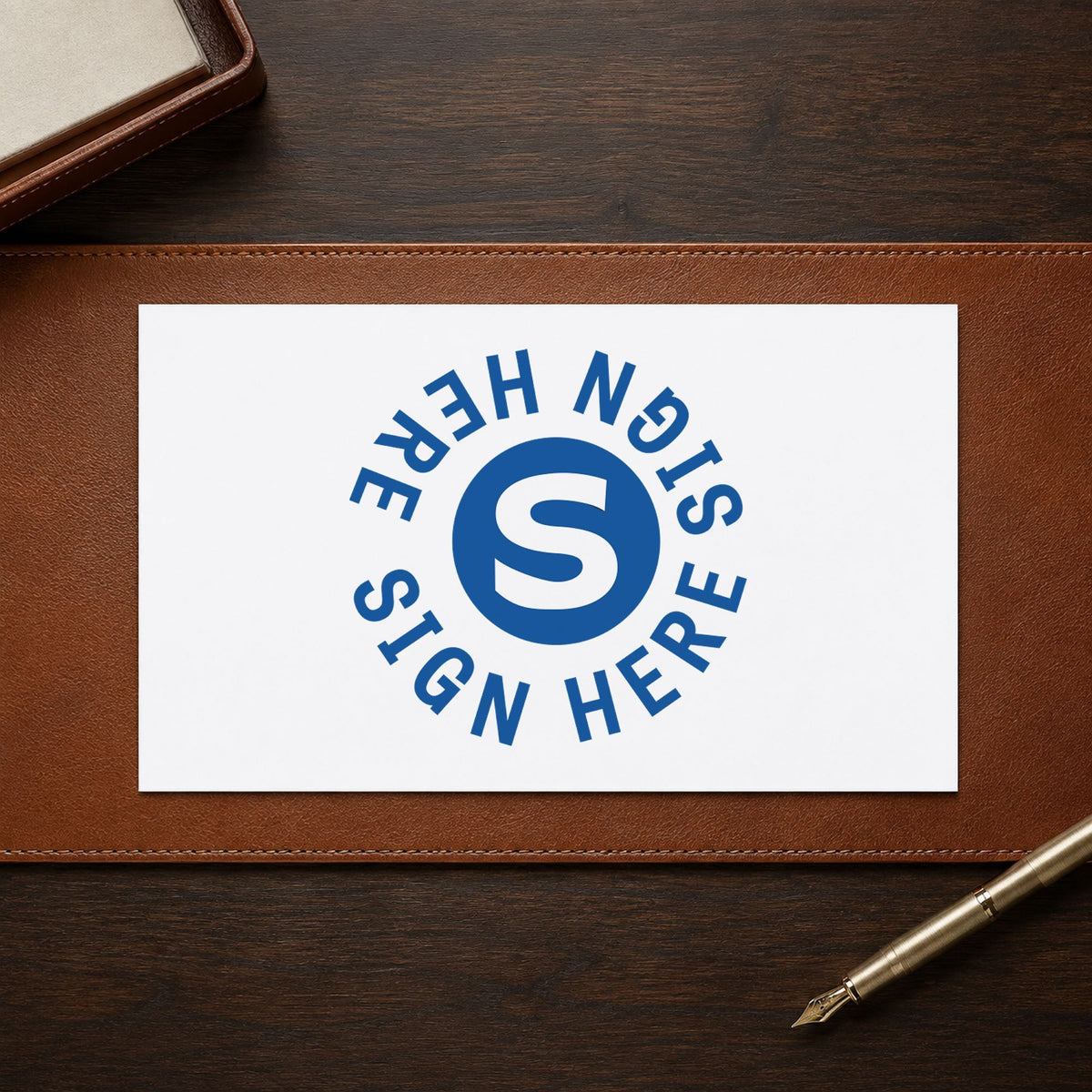 "Sign here" Xstamper stamp in use on paper, Approximately 5/8 in diameter round imprint