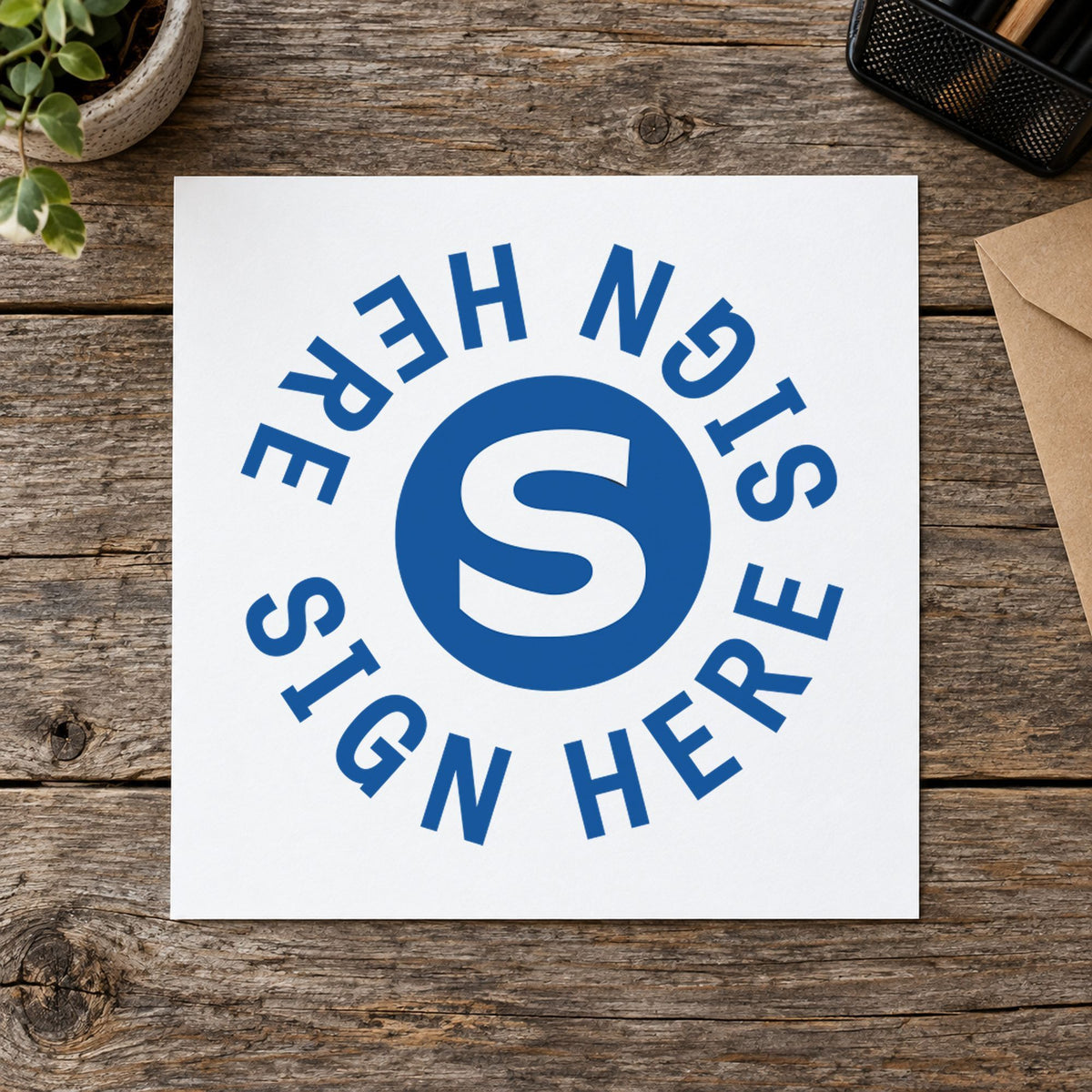 Pre-inked "Sign here" stamp marking paperwork in an office setting