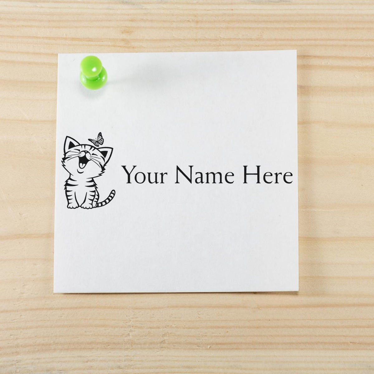 Custom cat name stamp and seal on white paper, black print with green push pin on light wood background