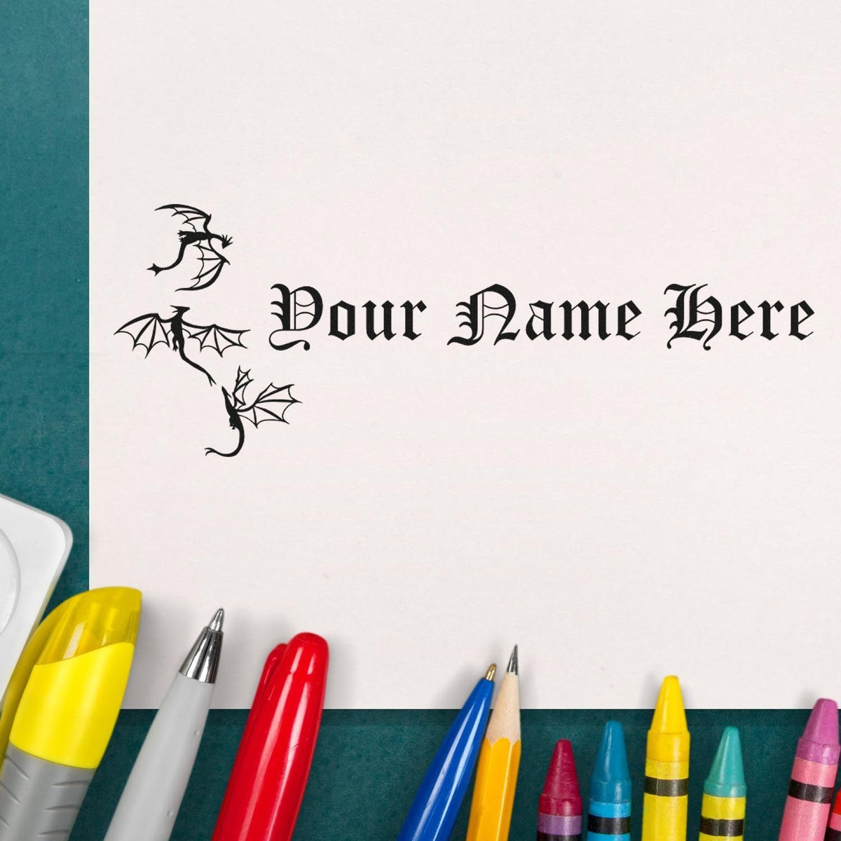 Black gothic dragon stamp and seal design with Your Name Here on white paper, surrounded by colorful pens.
