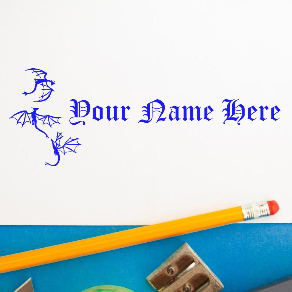Custom blue dragon stamp and seal with Your Name Here in gothic lettering on white paper beside a yellow pencil.