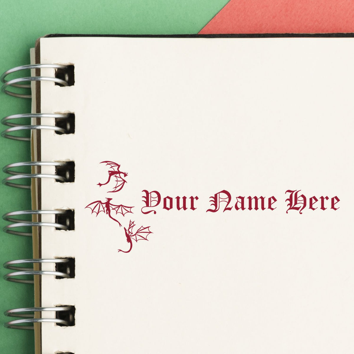Custom maroon dragon seal stamp with Your Name Here on a cream spiral notebook page.