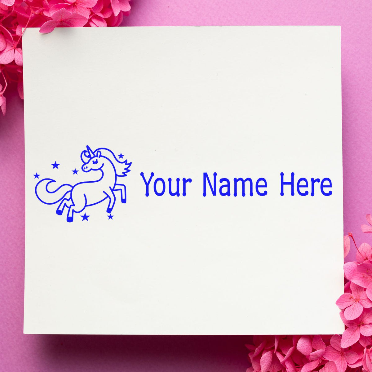 Personalized blue unicorn stamp and seal with Your Name Here on a white card, set against a pink floral background.
