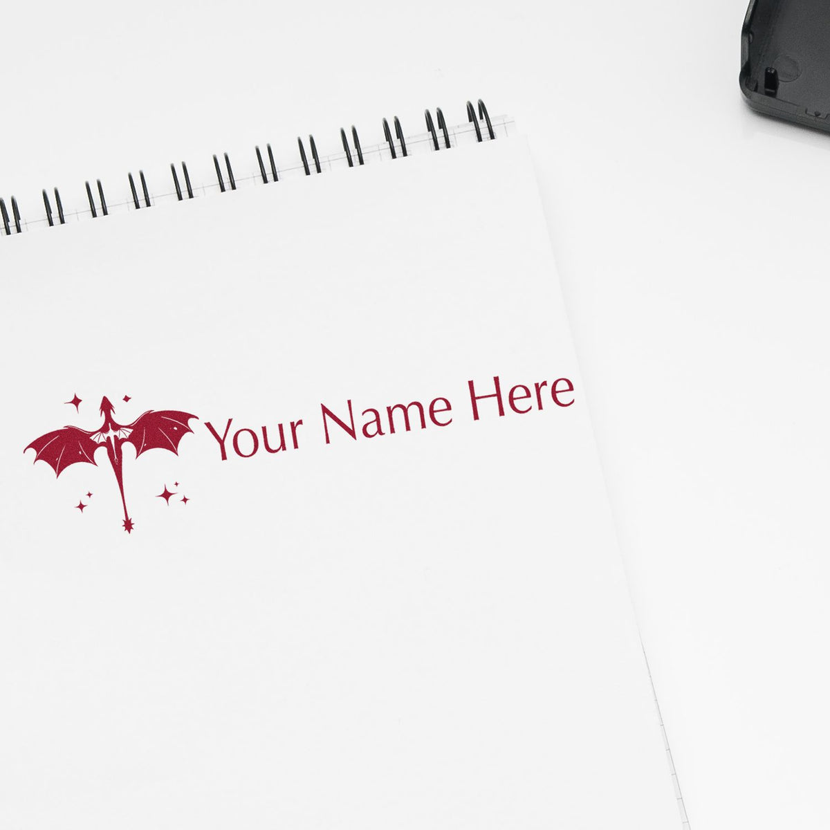 Personalized burgundy dragon stamp and seal on a white spiral notebook, with black stamp case.