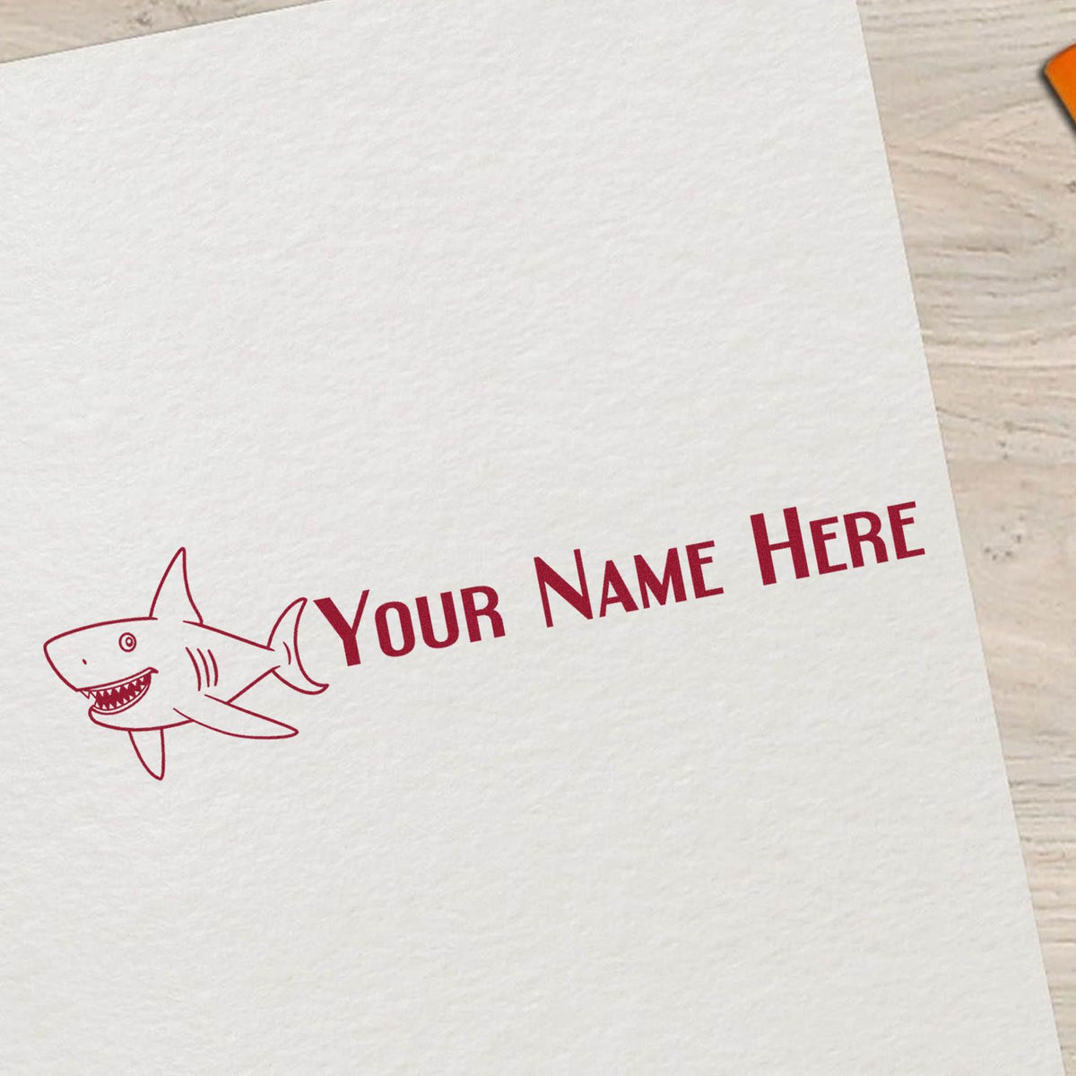 Maroon shark logo custom stamp with Your Name Here text on white paper, for seal or branding use.