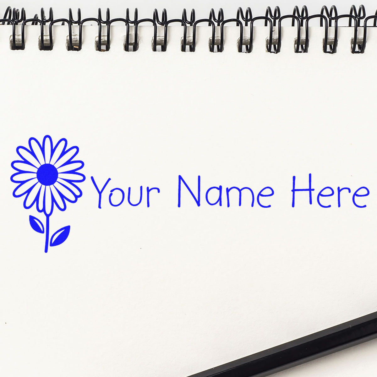 Blue custom stamp and seal design with flower logo and Your Name Here on a white notebook page.