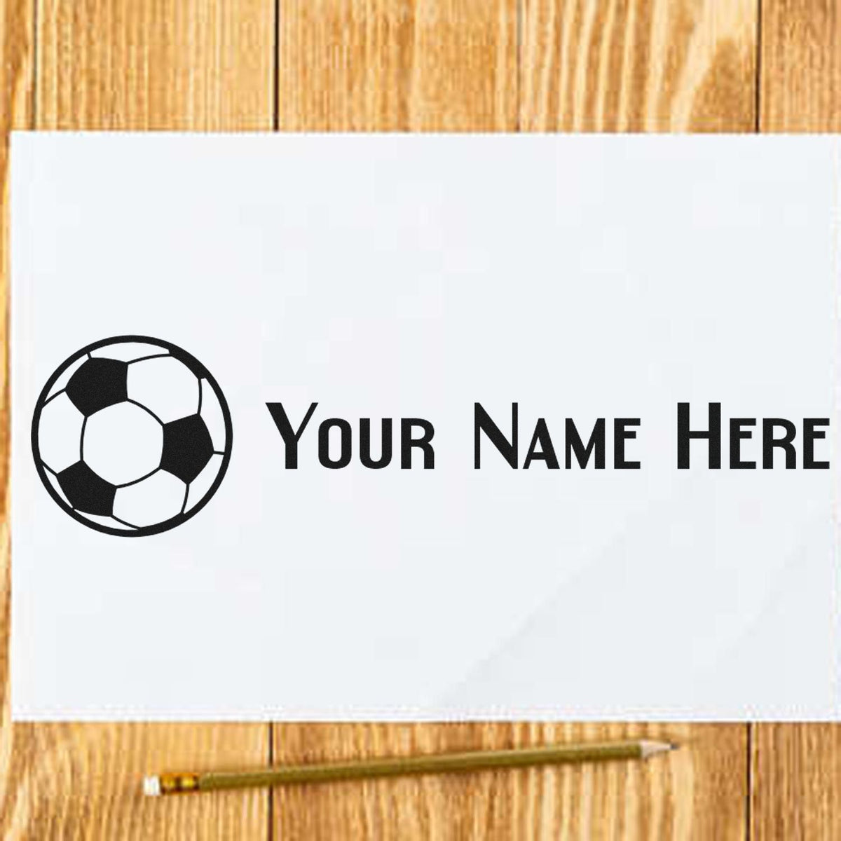 Custom stamp and seal with black soccer ball logo and Your Name Here on white paper over a wood table.