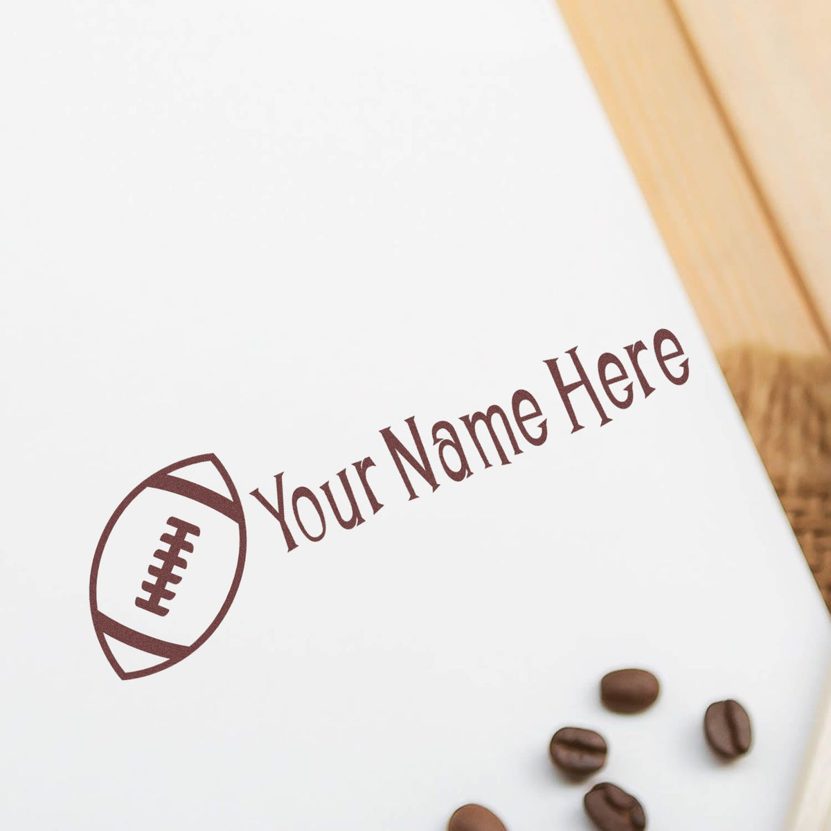 Brown football logo stamp and seal reading Your Name Here on white paper, with coffee beans.