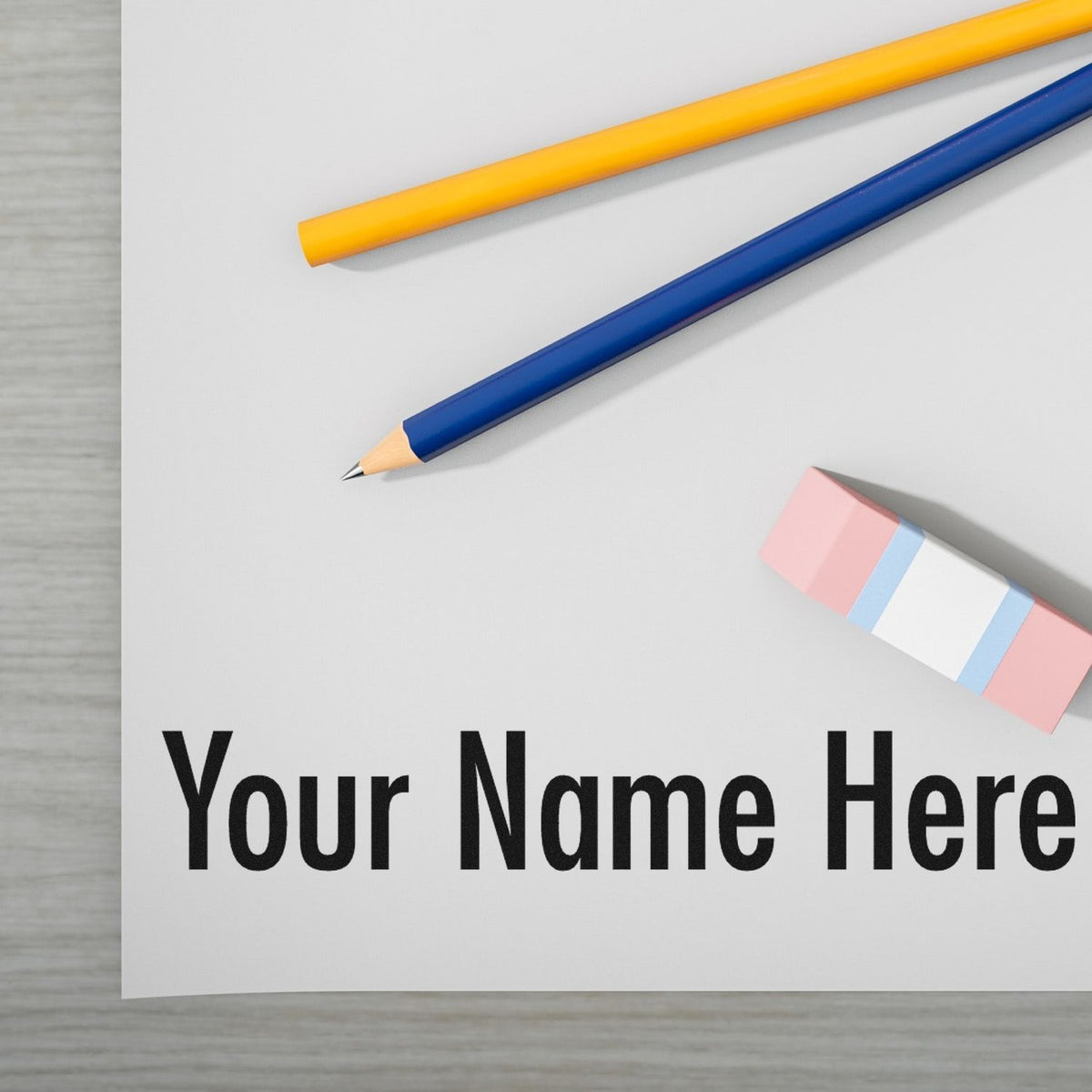 Custom stamp and seal mockup with yellow and blue pencils, pink eraser, and Your Name Here on white paper.