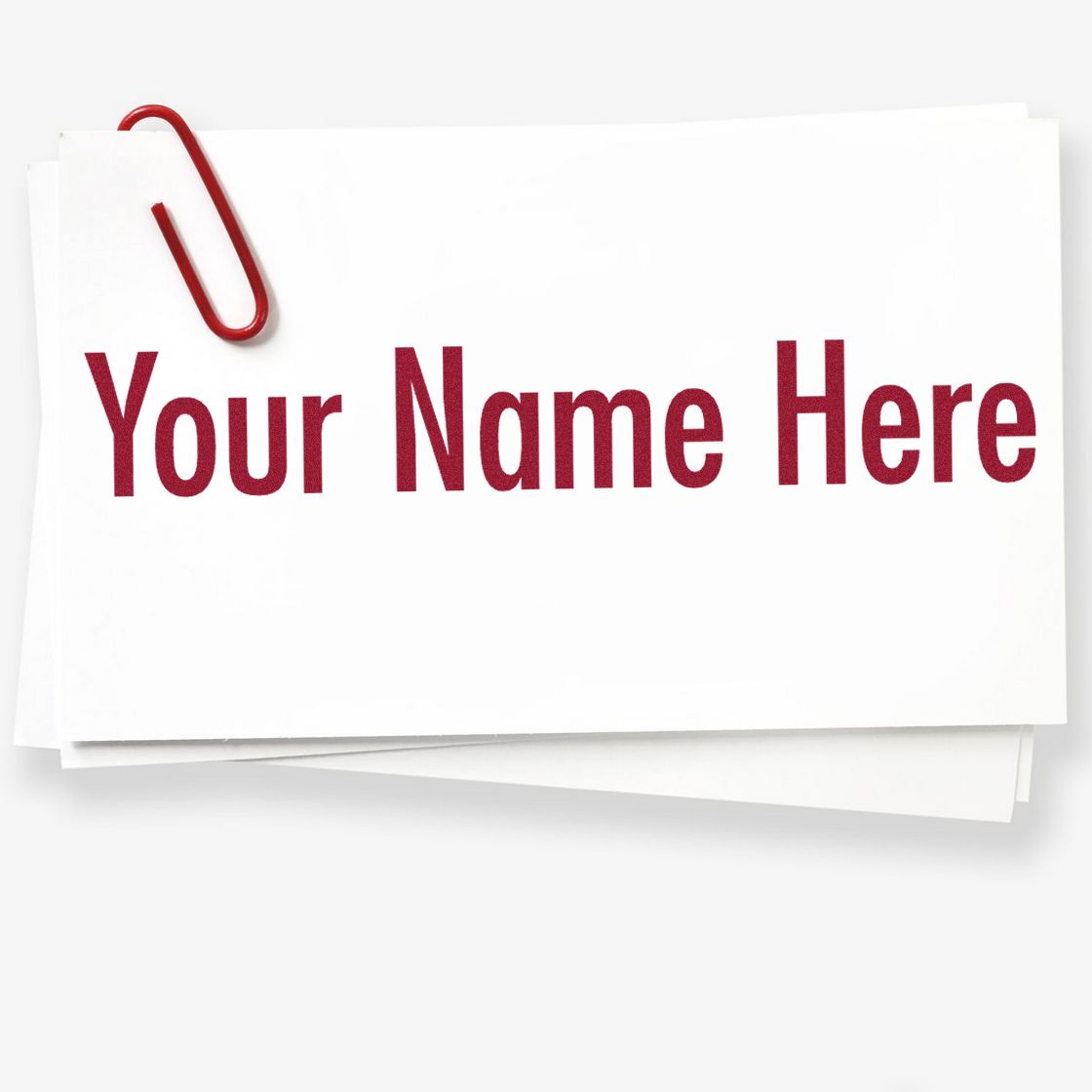Custom stamp and seal sample card with red paperclip and bold red Your Name Here text on white paper.
