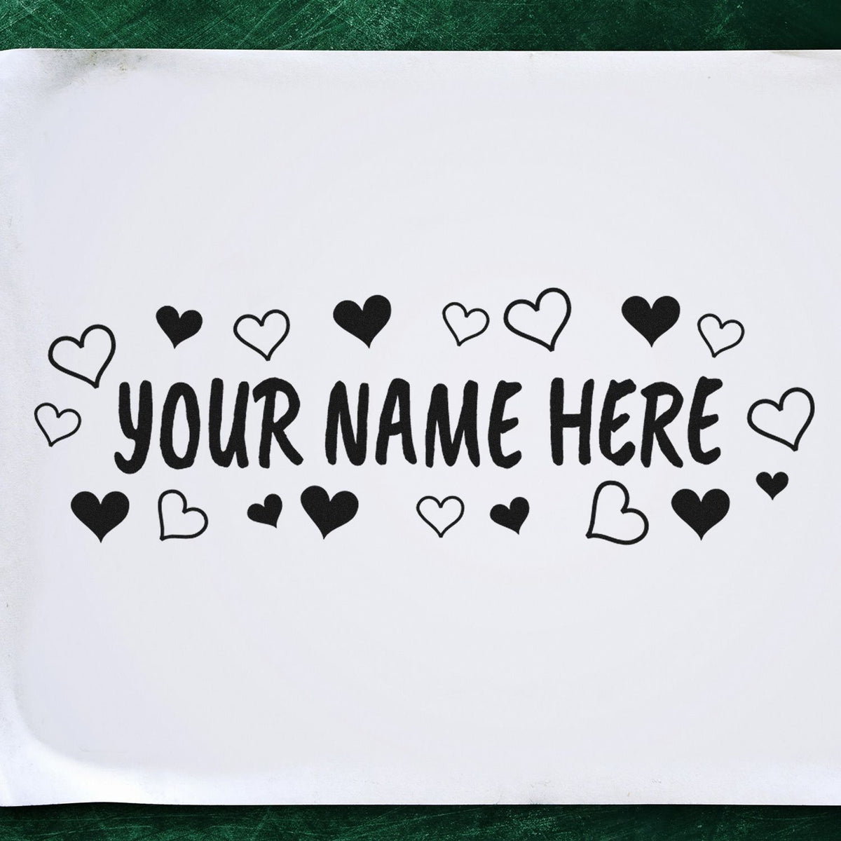 Black custom stamp and seal design with hearts and YOUR NAME HERE on white paper, on a green background.