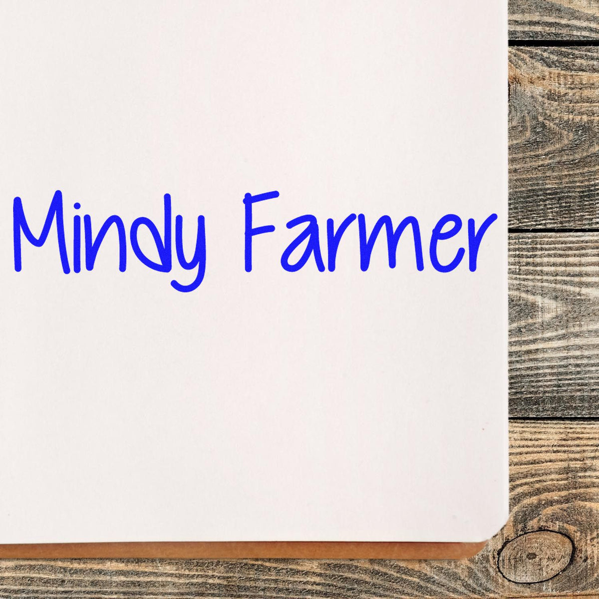 Blue Mindy Farmer custom stamp and seal on white card over rustic wood background.