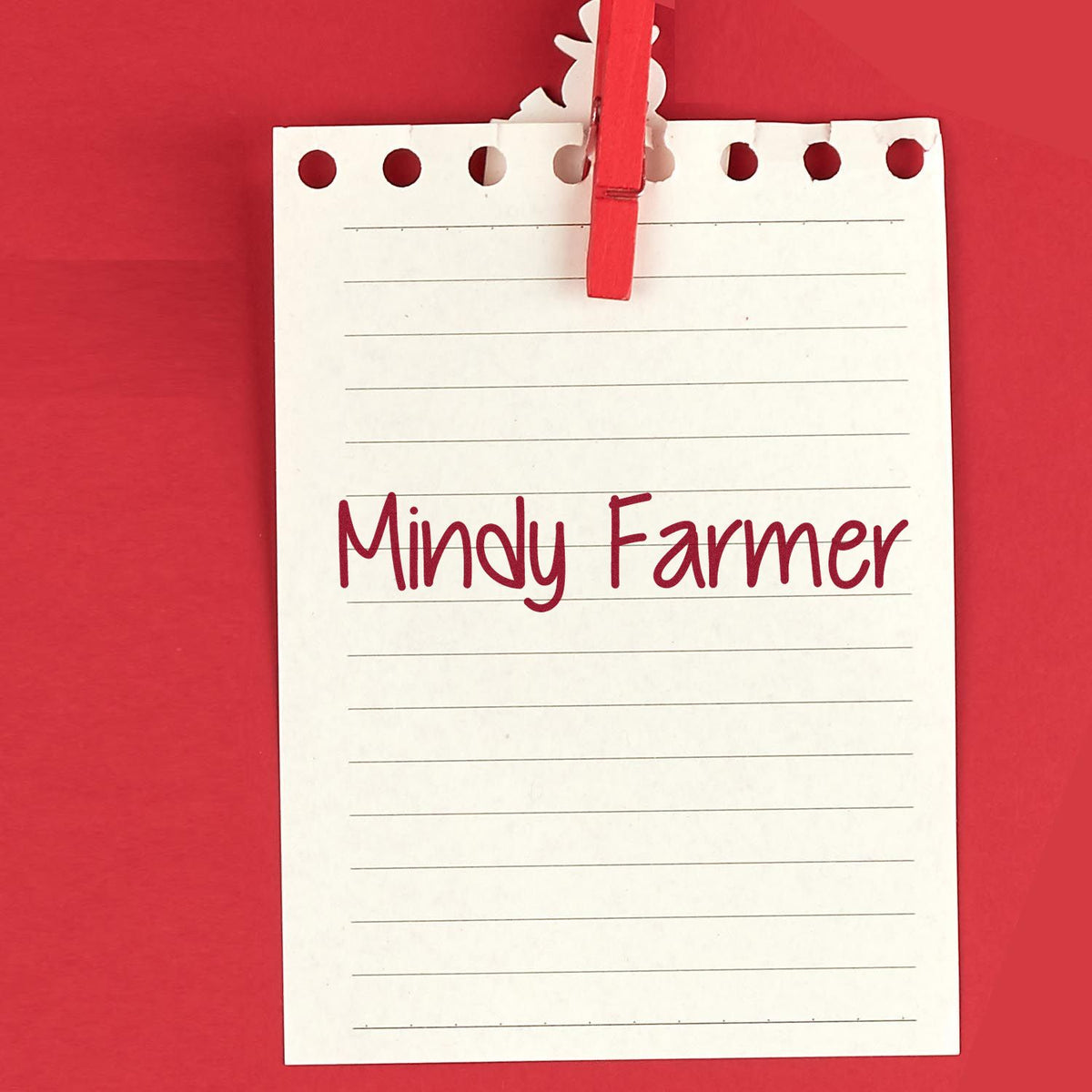 Red custom stamp and seal branding on white lined note paper clipped with a red clothespin against a red background.