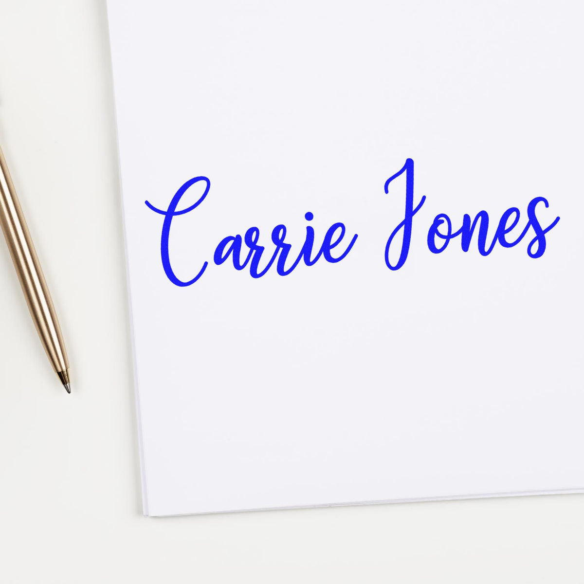 Blue cursive Carrie Jones custom stamp and seal on white paper, with a gold pen beside it.