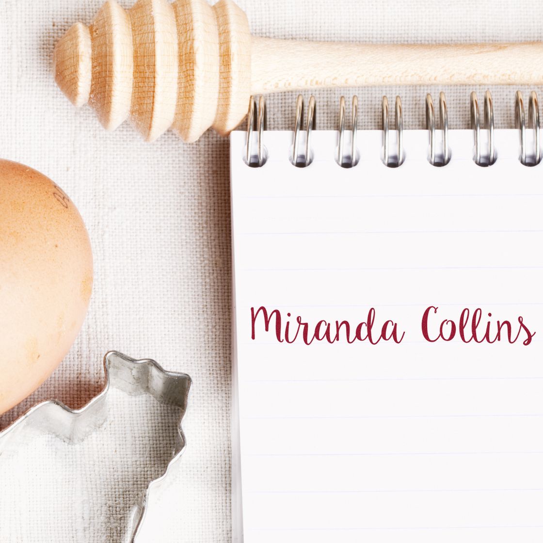 Custom stamp and seal products beside a white spiral notebook with burgundy Miranda Collins text on linen.