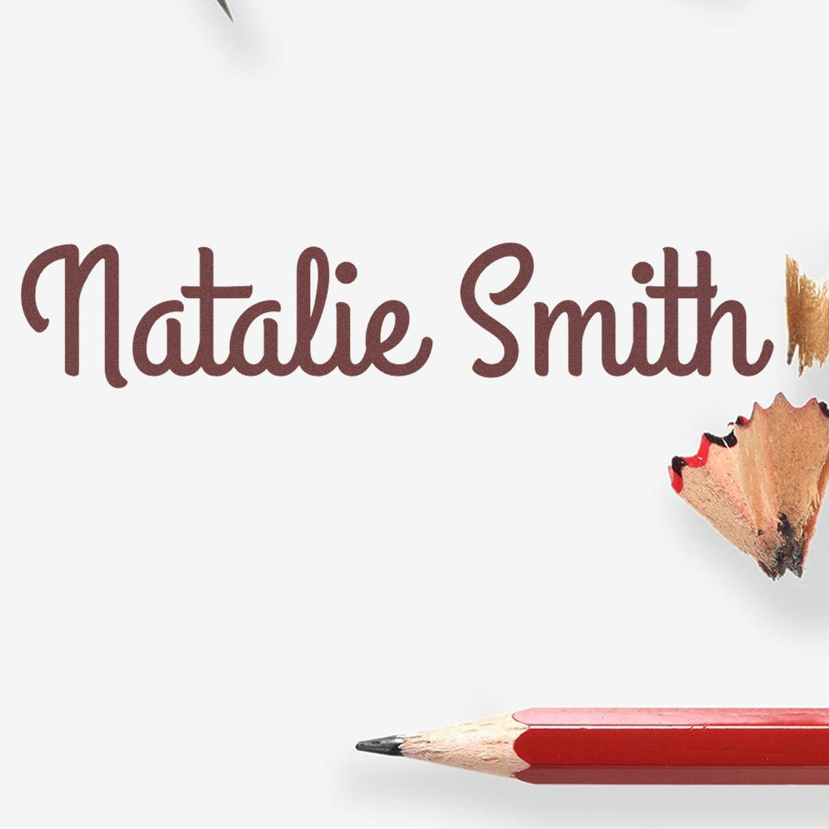 Personalized stamp and seal products with Natalie Smith in maroon script, white background, red pencil tip, and wood shavings.