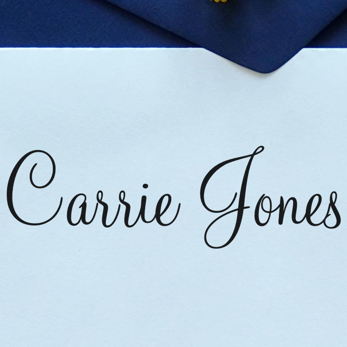 Custom stamp and seal with black cursive Carrie Jones on white paper, framed by a navy blue envelope flap.