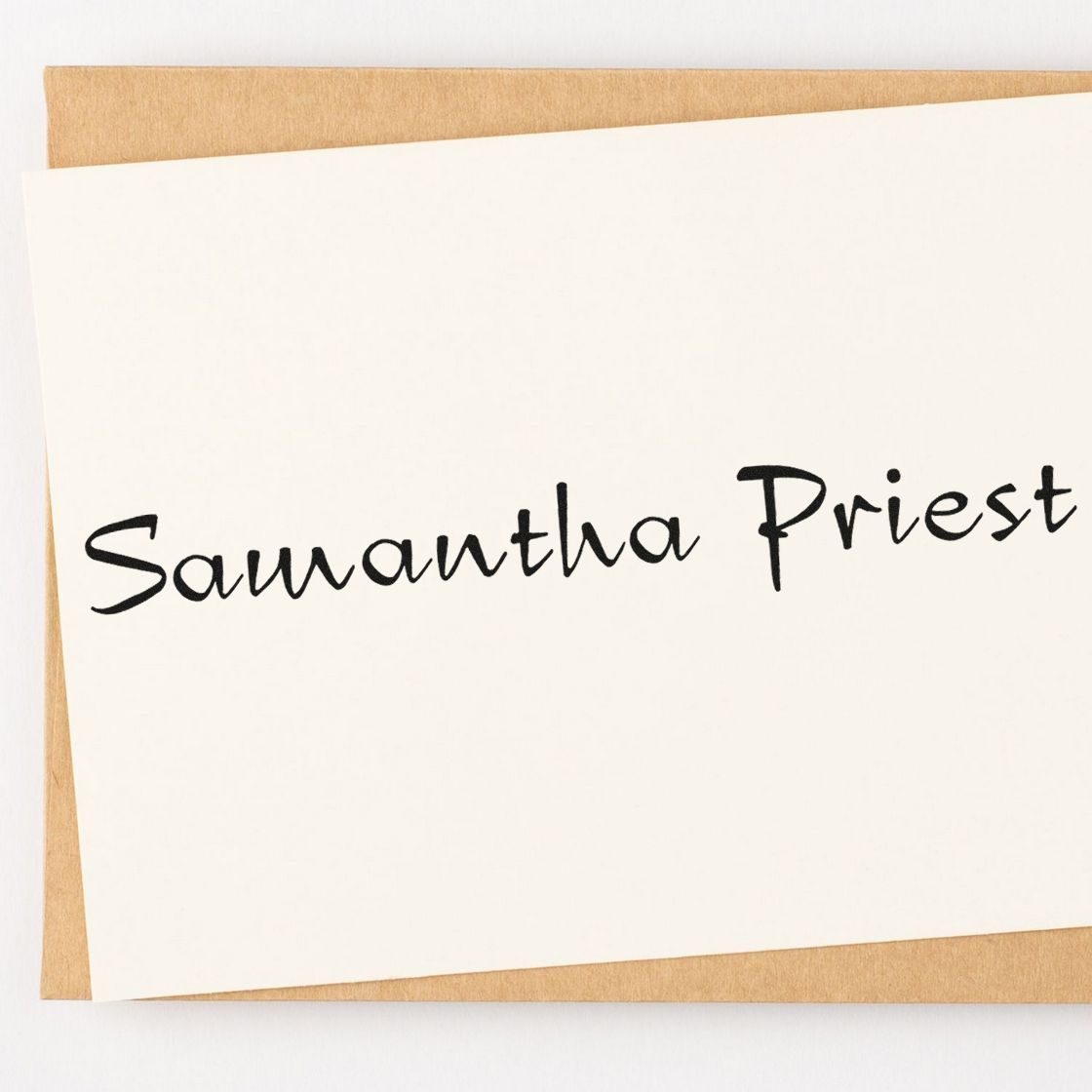 White custom stamp and seal card featuring black handwritten Samantha Priest on tan kraft backing.