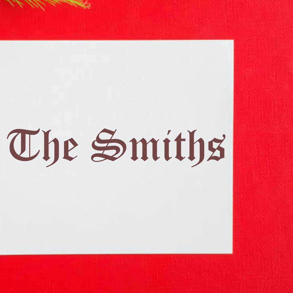 Custom rubber stamp seal with brown Gothic The Smiths text on a white block against a bright red background.