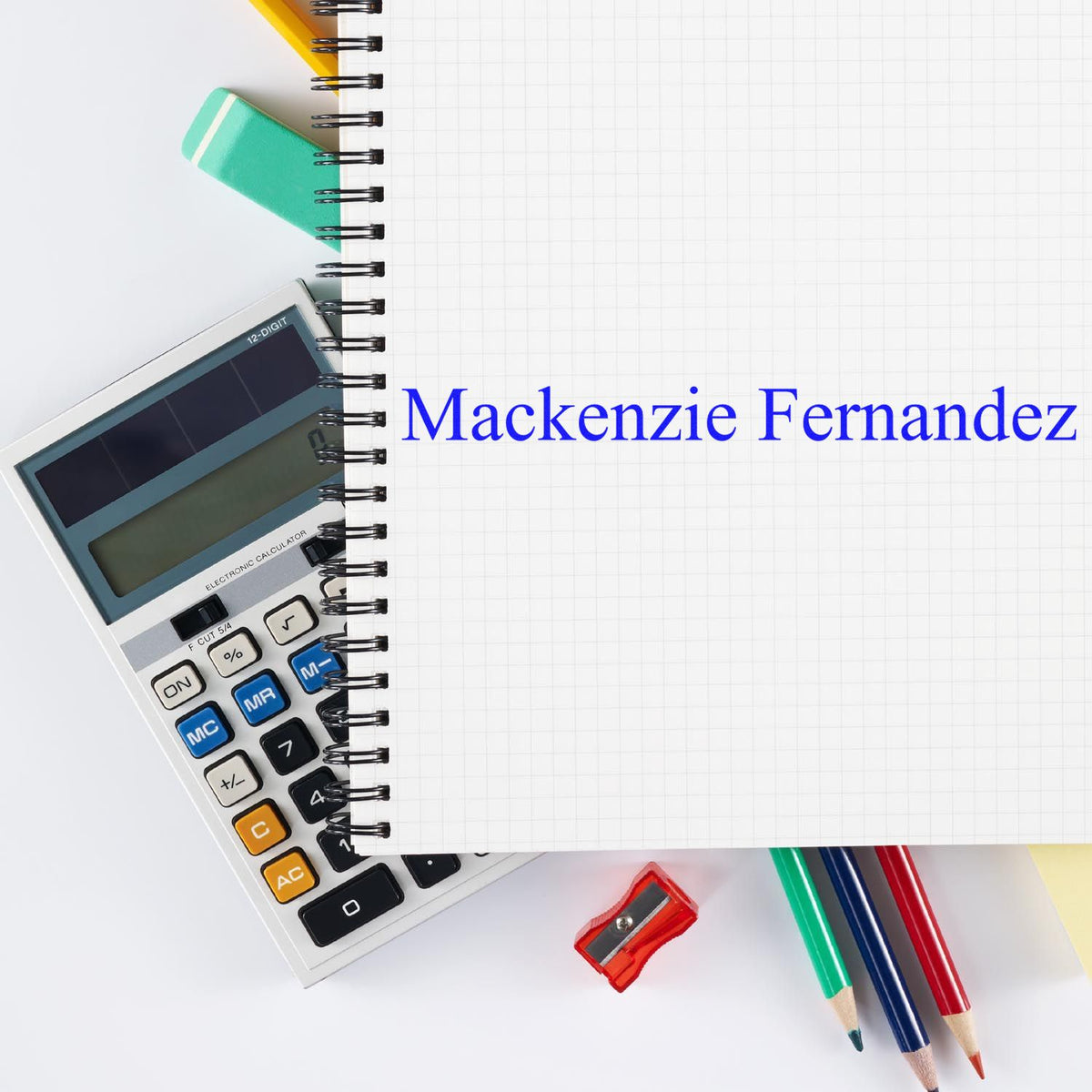 Blue Mackenzie Fernandez stamp and seal on graph paper notebook, with calculator, teal eraser, and colored pencils.
