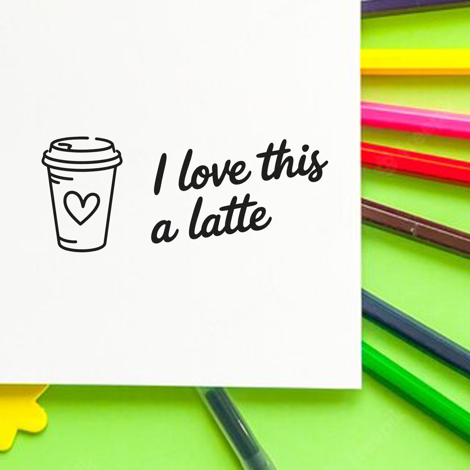 Black custom stamp with coffee cup icon and I love this a latte in black, beside neon green and colorful pens.